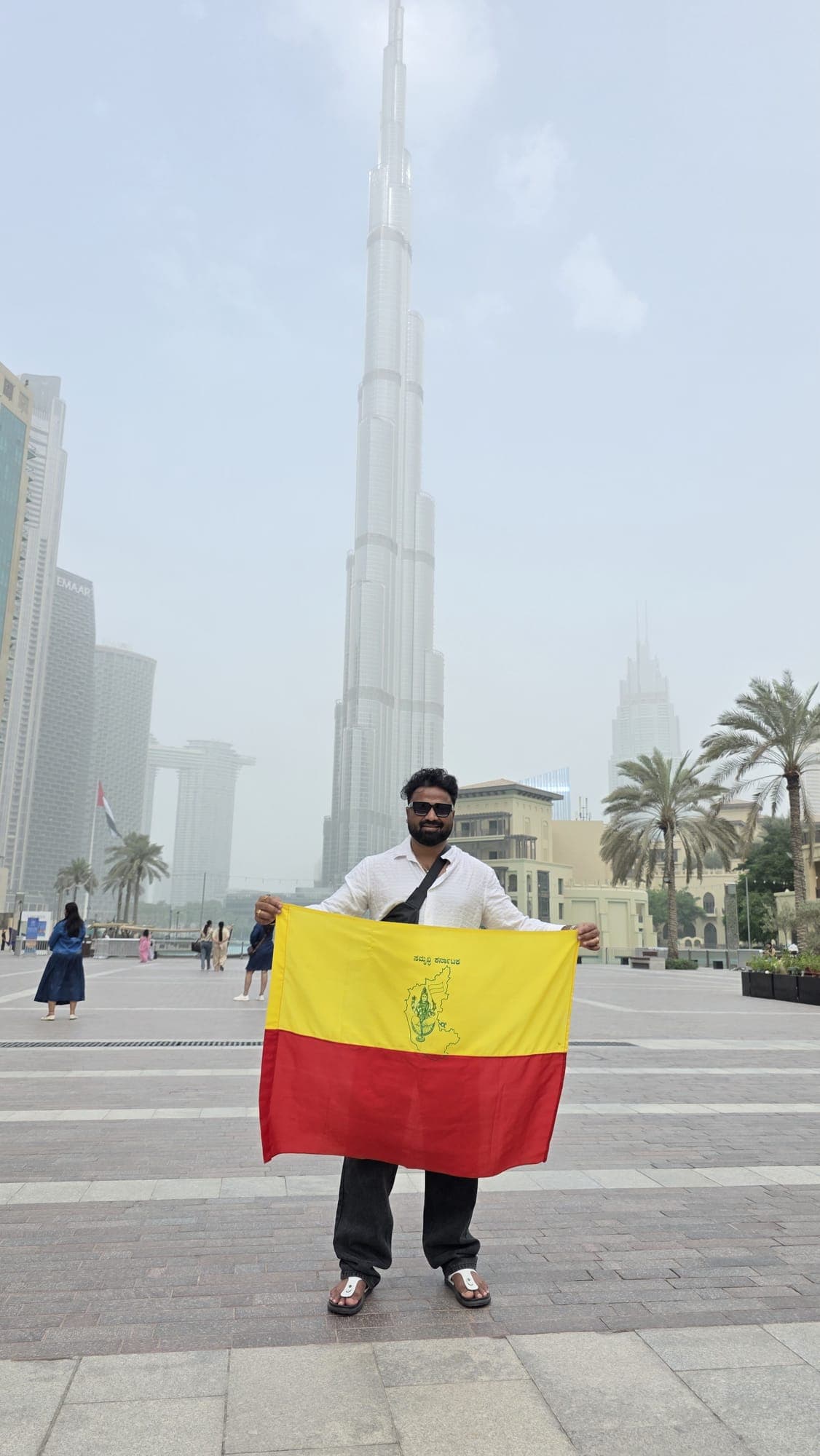 Traveller holding the Karnataka flag in front of the Burj Khalifa, Dubai