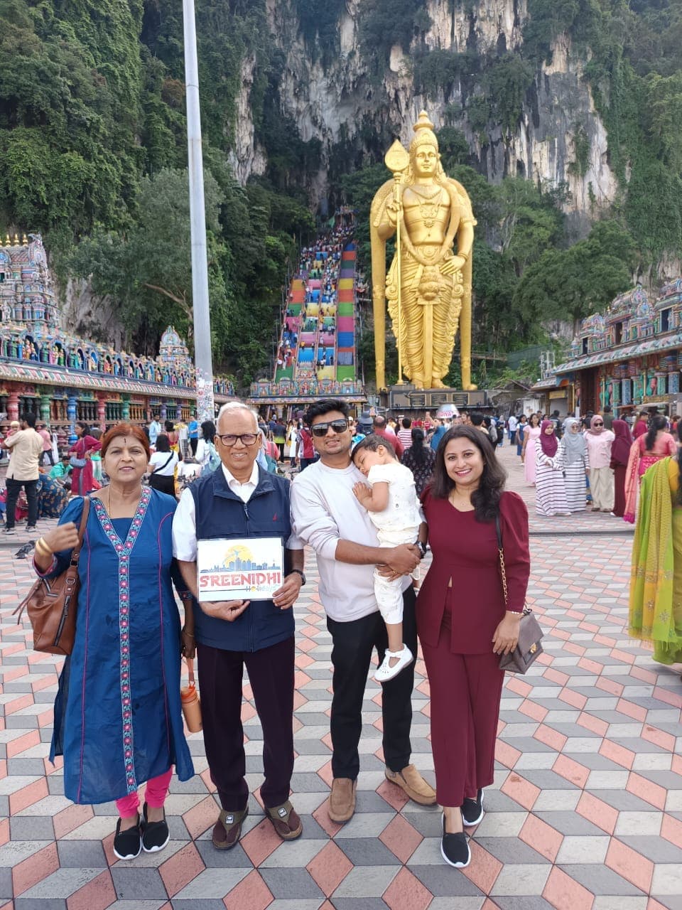 Travellers at Batu Caves with the golden Murugan statue, Malaysia
