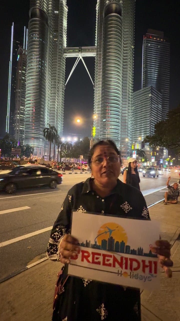 Traveller with the Sreenidhi Holidays banner at the Petronas Towers, Kuala Lumpur